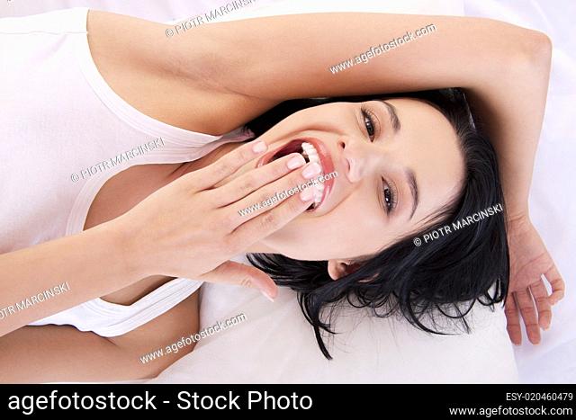 Happy sensual young woman lying in bed