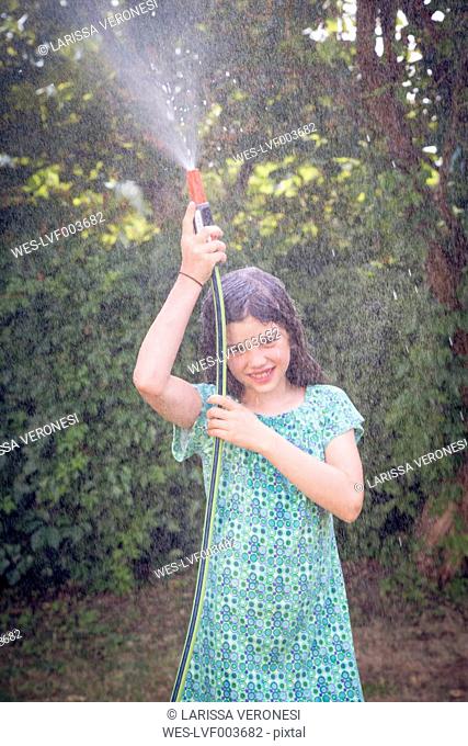 Girl cooling herself with garden hose