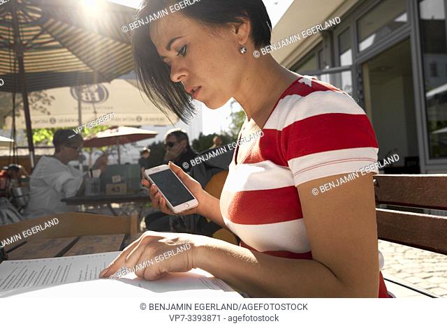 woman checking menu card in outdoor restaurant, at Herrenchiemsee, Chiemsee, Bavaria, Germany