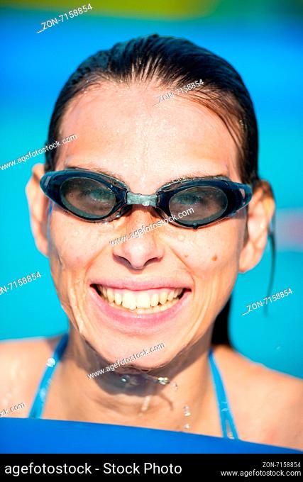 Portrait of a young woman in goggles in swimming pool. Blue water. Outdoor summer woman