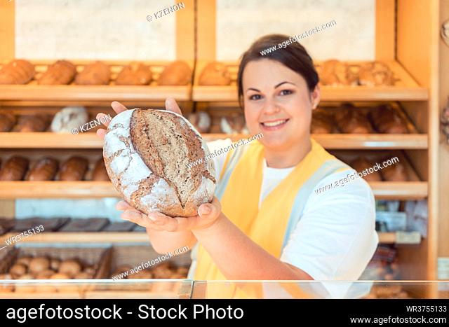 Saleslady in bakery shop presenting bread to potential buyer