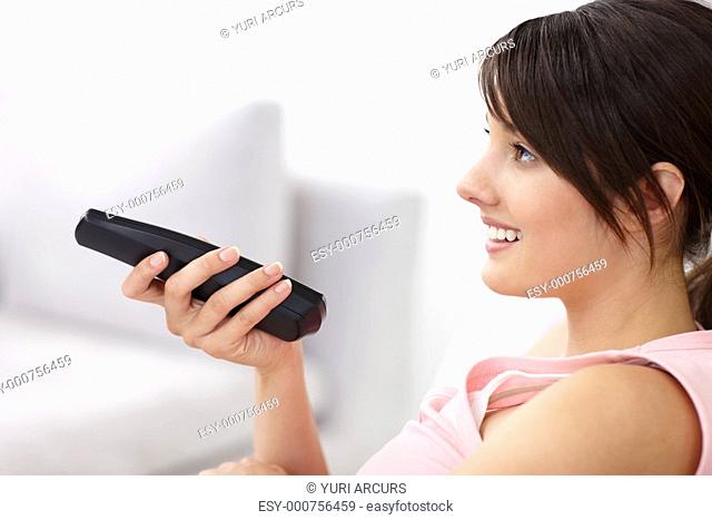 Cute young female changing the television channels using a controller