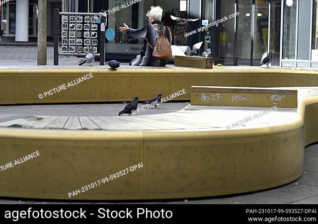 16 October 2023, North Rhine-Westphalia, Wuppertal: A woman sits on the shiny gold benches in the pedestrian zone of Elberfeld