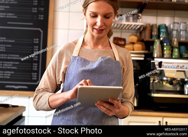 Coffee shop owner using tablet PC in cafe