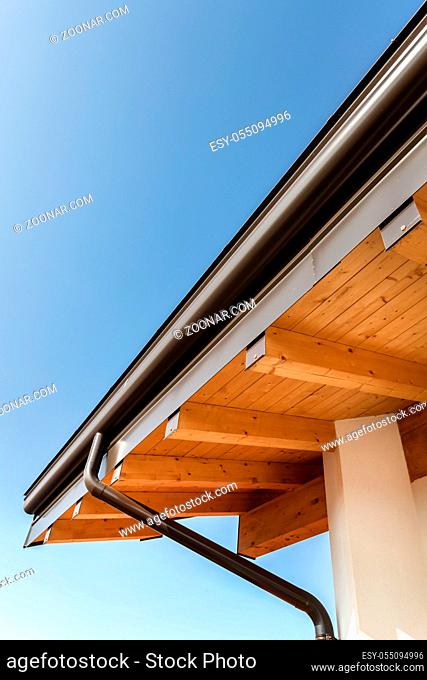 New wooden warm ecological house roof with steel gutter rain system. Professional construction and drainage pipes installation. Eco materials