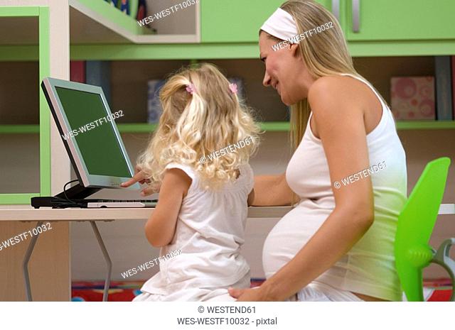 Pregnant mother and daughter 3-4 using computer