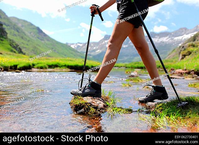 Close up portrait of a trekker legs crossing river walking with poles