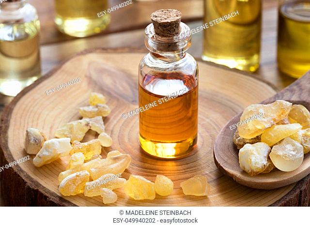 A bottle of frankincense essential oil with frankincense resin on a wooden table