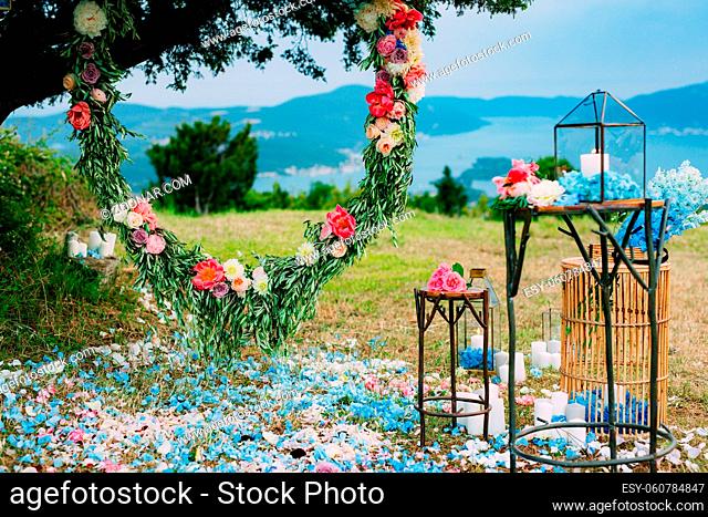 Round wedding arch of flowers and olive branches. Hanging on the tree, near the fort of Gorazda in Montenegro. Overlooking the Bay of Kotor at sunset