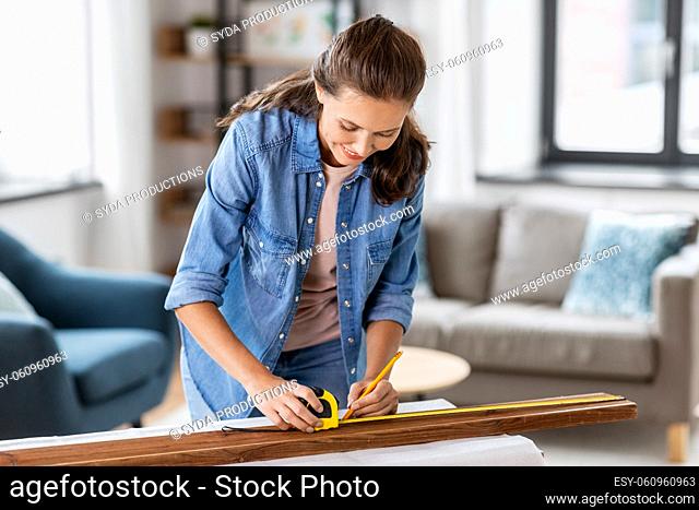 woman with ruler measuring wooden board at home