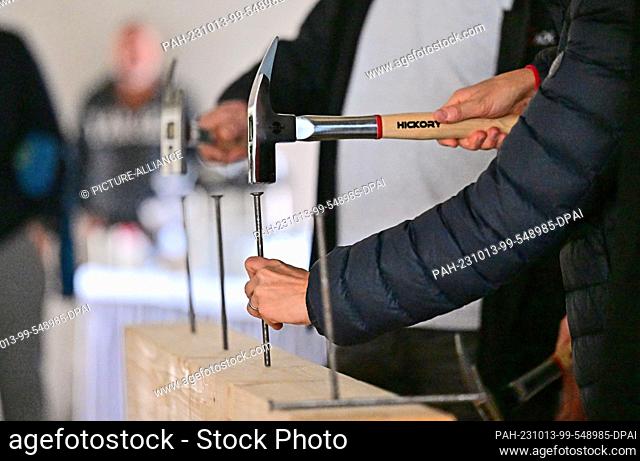 PRODUCTION - 12 October 2023, Thuringia, Erfurt: Nails are hammered in at a construction site on the day of the topping-out ceremony