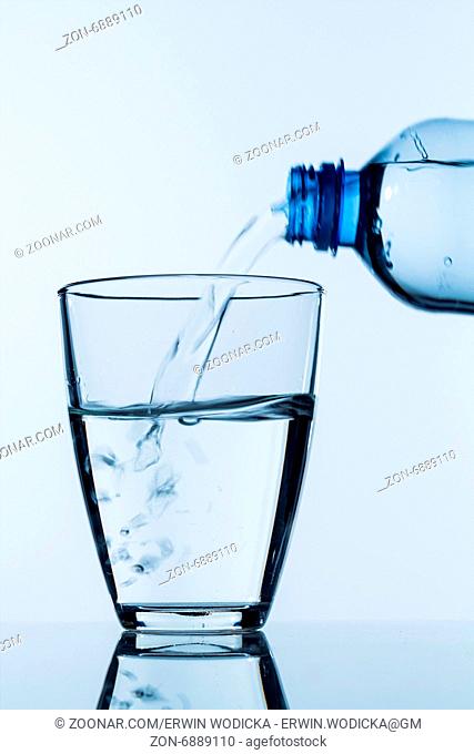 Aus einer Flasche wird Wasser in ein Glas gegossen, Symbolfoto für Trinkwasser, Bedarf und Verbrauch