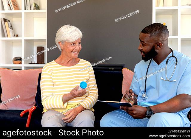 Male health worker with clipboard discussing with caucasian senior woman over medication dose