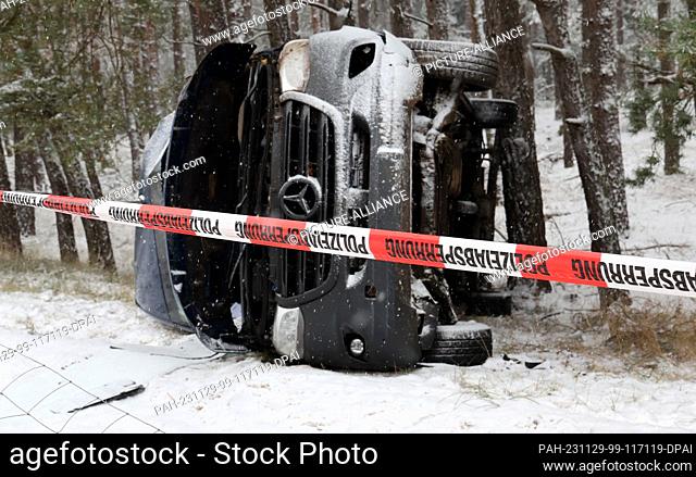 29 November 2023, Mecklenburg-Western Pomerania, Malchow: A van involved in an accident lies next to the A19 highway in the snow-covered forest; the adverse...