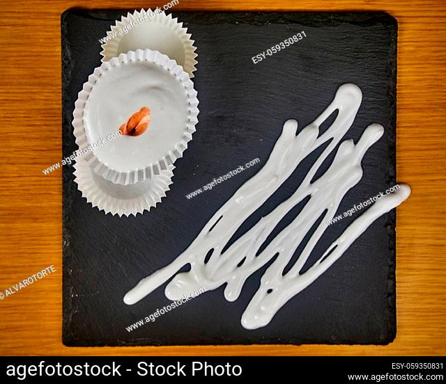 Several Raw French dessert Meringues with Strawberry sauce and Meringue syrup topping on a wooden table and a black slate board. Top View