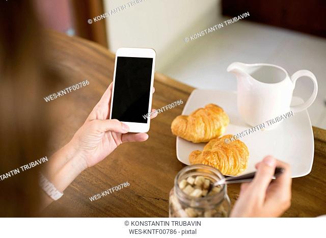 Woman at breakfast table using cell phone