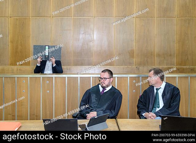 03 July 2020, Lower Saxony, Hanover: The accused sits behind his defenders Daniel Brunkhorst (M) and Sven Tamoschus and holds a file folder in front of his face...