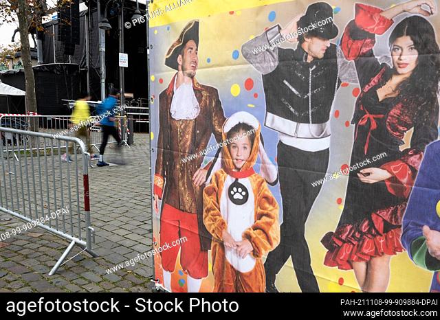 08 November 2021, North Rhine-Westphalia, Cologne: Pedestrians walk past barrier grids during set-up work for the carnival kick-off under Corona conditions on...