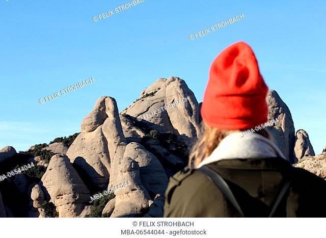 The cap of a young woman fitting perfectly in the mountain panorama near Montserrat