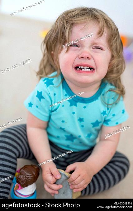 Little girl sits crying on the floor