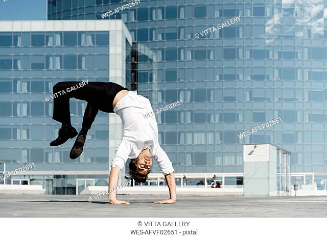Artist doing handstand on roof terrace