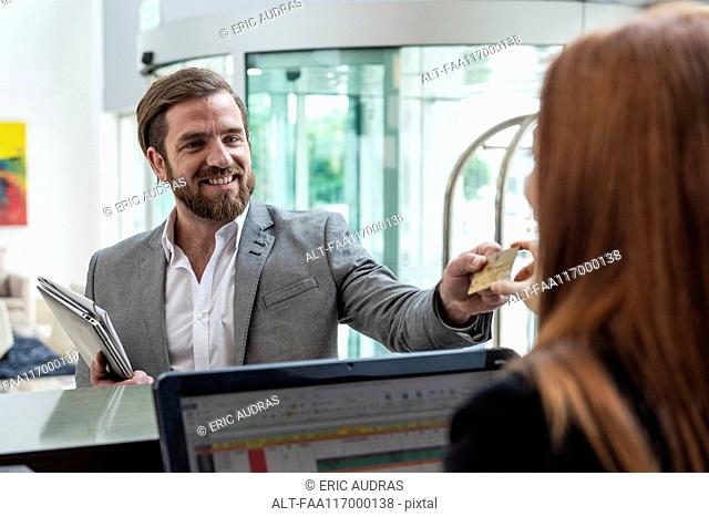 Businessman giving credit card to female receptionist