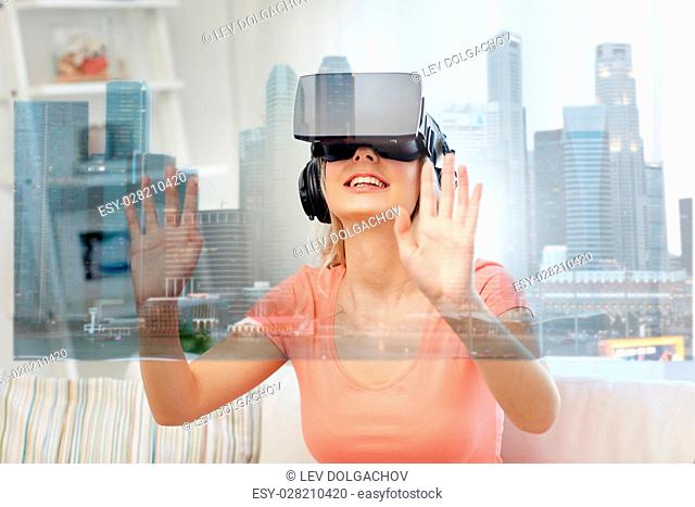 technology, augmented reality and entertainment concept - happy young woman in virtual headset 3d glasses and headphones playing game at home with singapore...