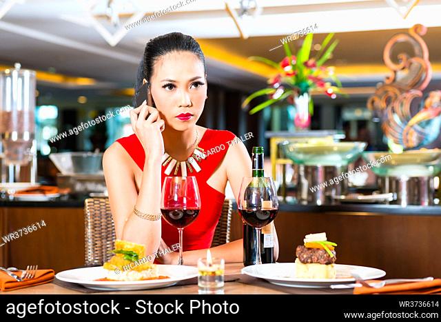 Asian Woman phoning in restaurant