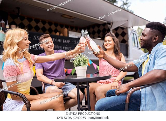 friends clinking bottles with drinks at food truck