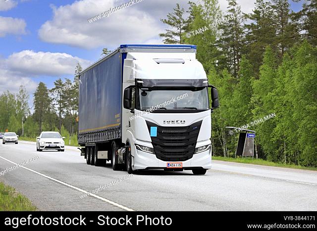 New, white gas-powered Iveco S-Way Natural Power, NP, truck in front of semi trailer on highway 25 on a sunny day. Raasepori, Finland. May 27, 2021