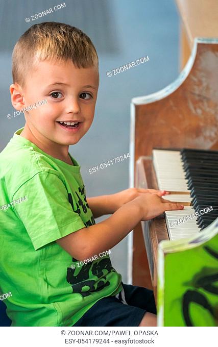 Little young caucasian boy playing on the piano outside train station