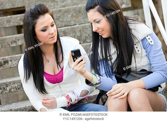 Two attractive young women talk about incoming sms message