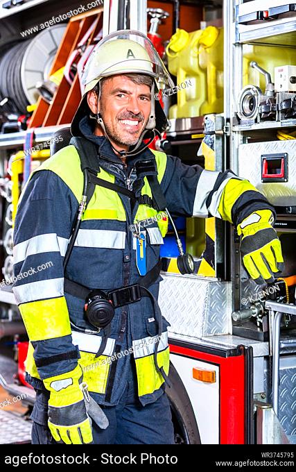 Fire fighter in uniform leaning at vehicle of fire department
