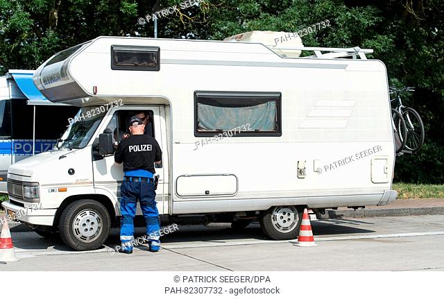 A police officer inspects a camper van by the A5 highway near Neuenburg,  Germany, 22 July 2016. Because many campers and trailers are overloaded during summer