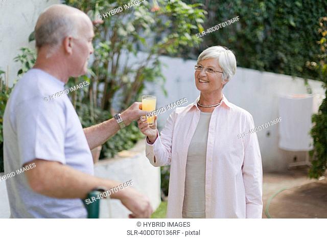 Older couple drinking juice in backyard