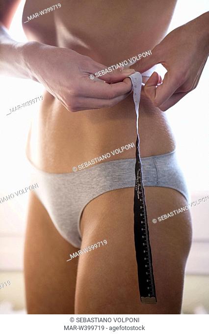 young woman measuring waist with a measuring tape