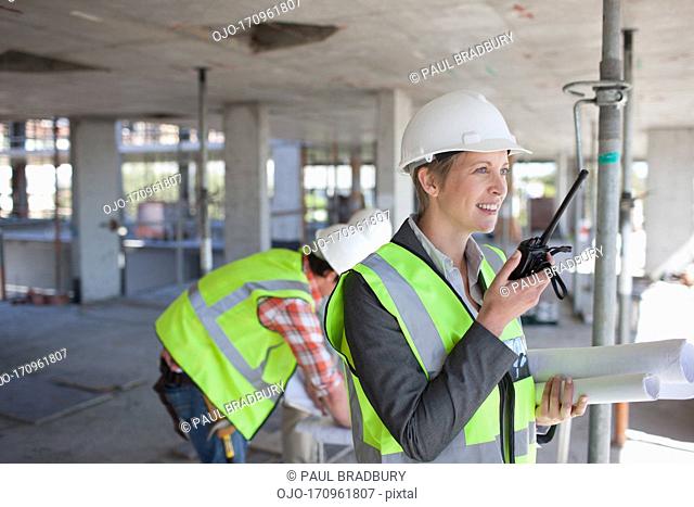 Businesswoman talking on walkie talkie on construction site