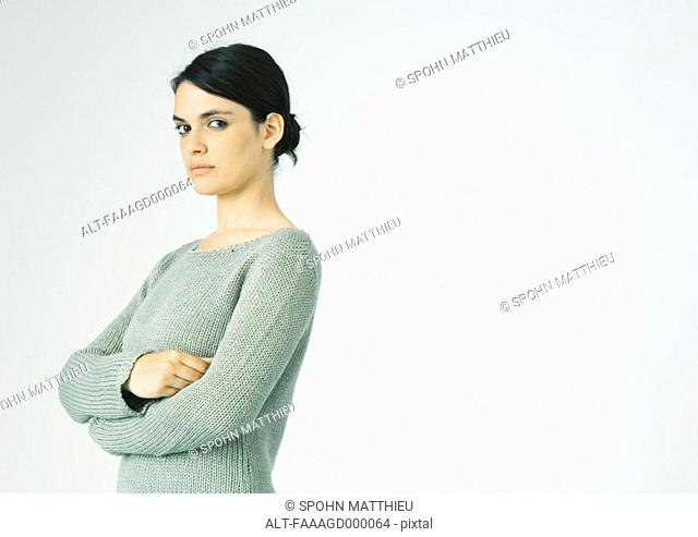 Young woman standing with arms crossed, looking at camera