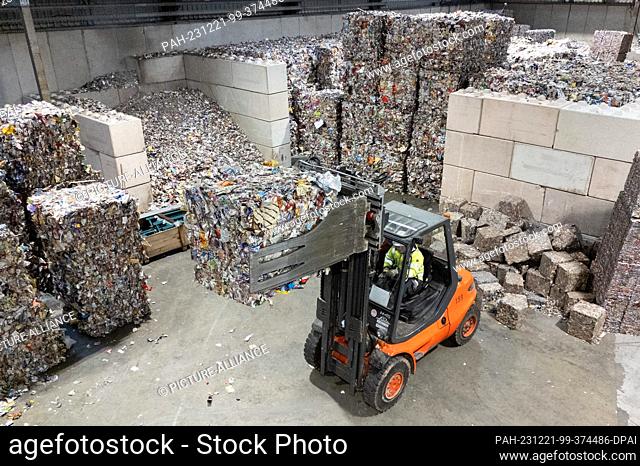 21 December 2023, Saxony, Freiberg: An employee uses a forklift to lift aluminum waste pressed into bales from the yellow garbage can in a hall at the new Plant...