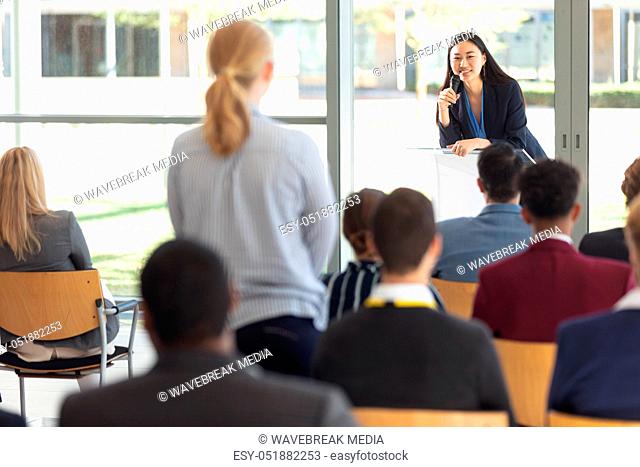 Young Asian female executive doing speech in conference room, answering question