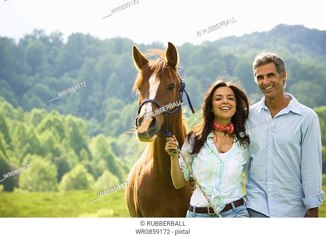 Portrait of a man and a woman standing with a horse
