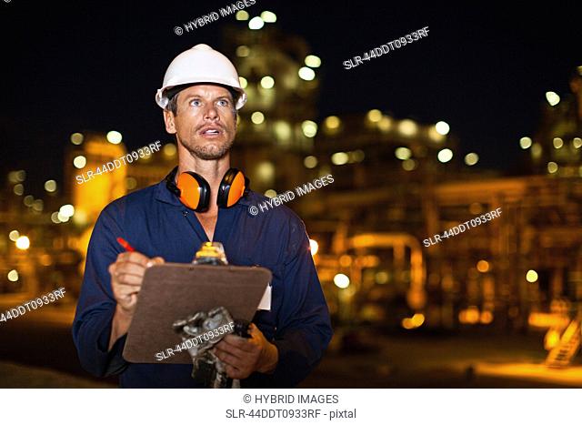 Worker with clipboard at oil refinery
