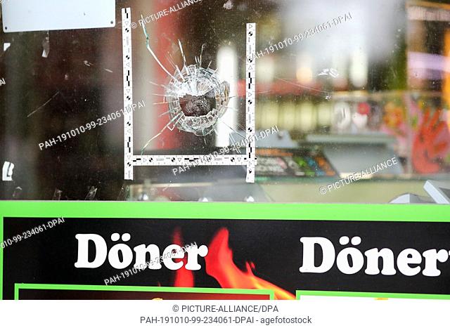 10 October 2019, Saxony-Anhalt, Halle: Police markings stick around a bullet in the window of a kebab shop in Halle. During attacks in the middle of Halle an...
