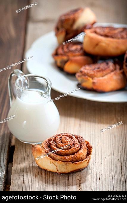 Cinnamon rolls on a plate and small jugs of milk