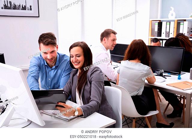 Portrait Of A Young Smiling Businesspeople Discussing On Document While Working In Office