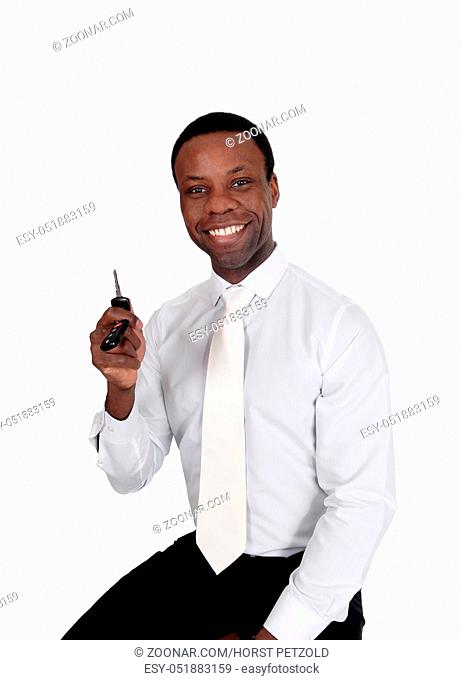 A young handsome African American man sitting in a white shirt and tie holding up his new car key's, isolated for white background