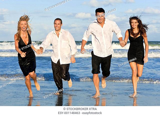 Four Young People, Two Couples, Having Fun Running On Beach