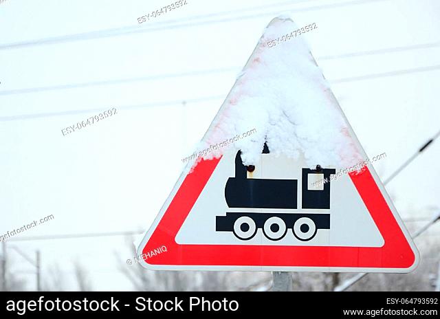 Railway crossing without barrier. A road sign depicting an old black locomotive, located in a red triangle