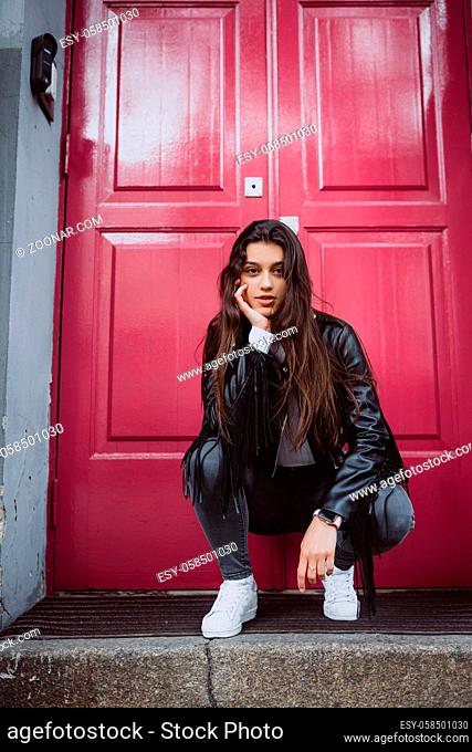 Portrait of a smiling young woman outdoor against a red door