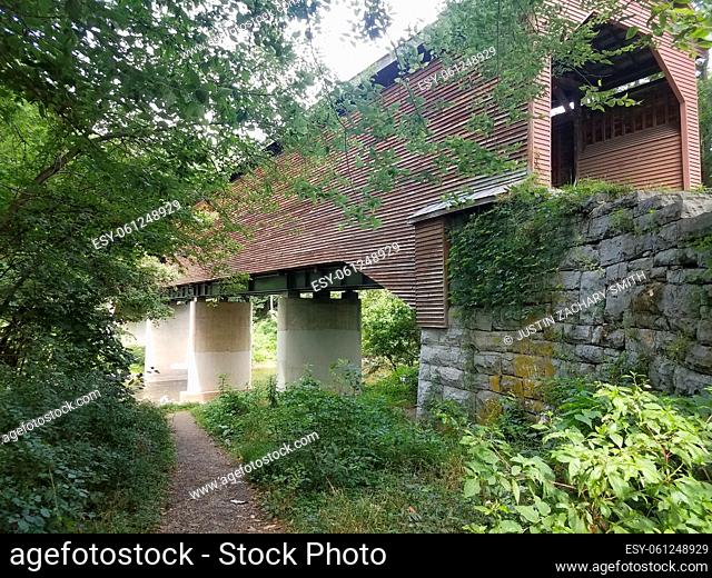old wood covered bridge with stone supports and river below